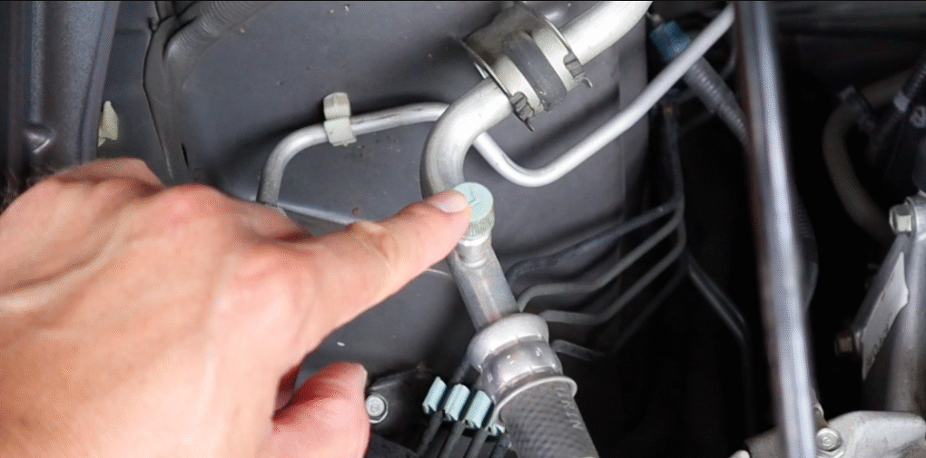 DIY car A/C recharge showing the low-pressure port on the aluminum A/C line